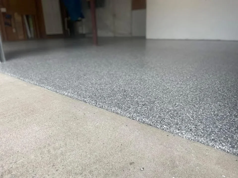 Gray speckled epoxy floor coating with clean edge transition on concrete garage floor