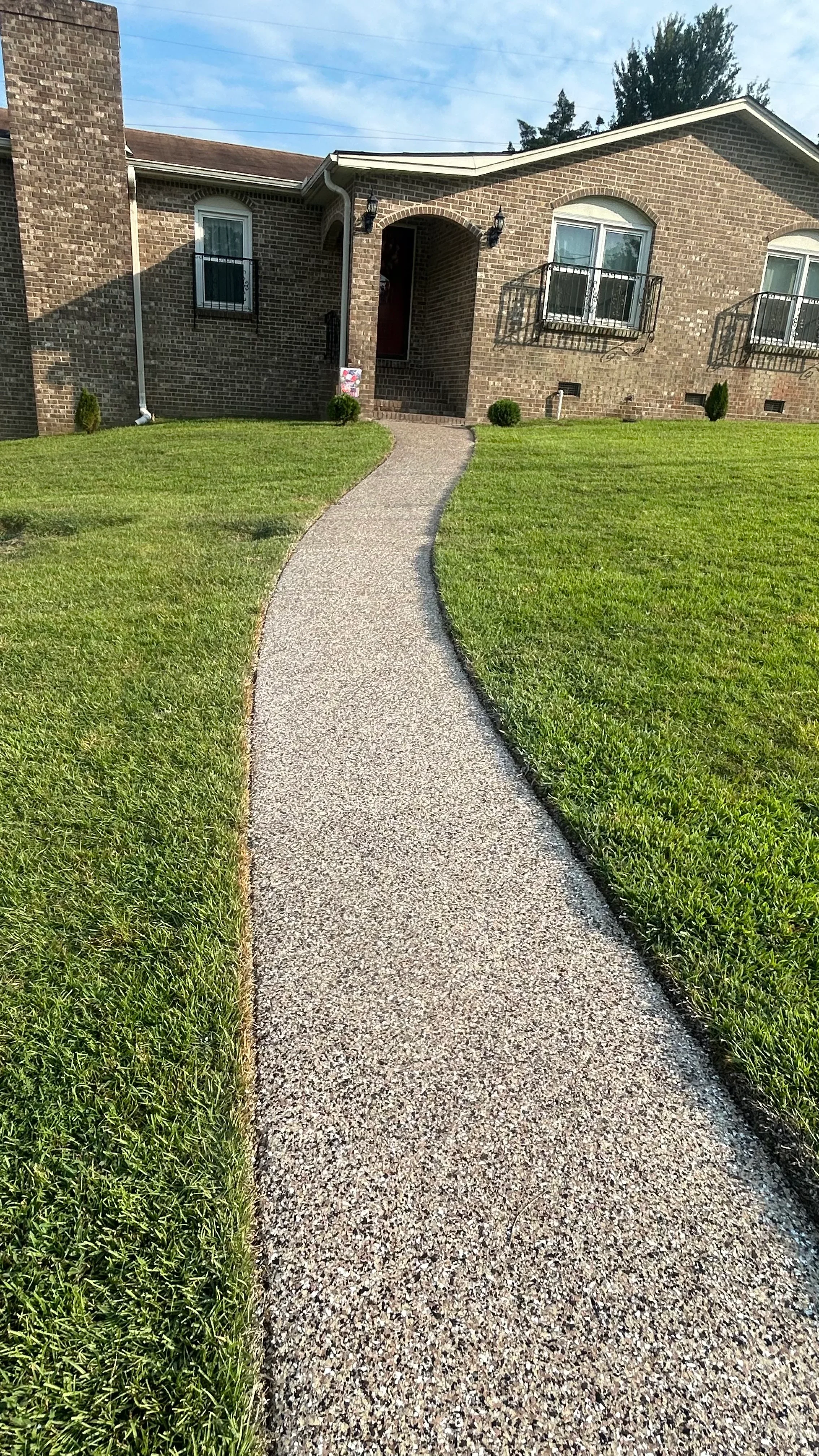 Finished concrete walkway with aggregate finish leading to brick home entrance
