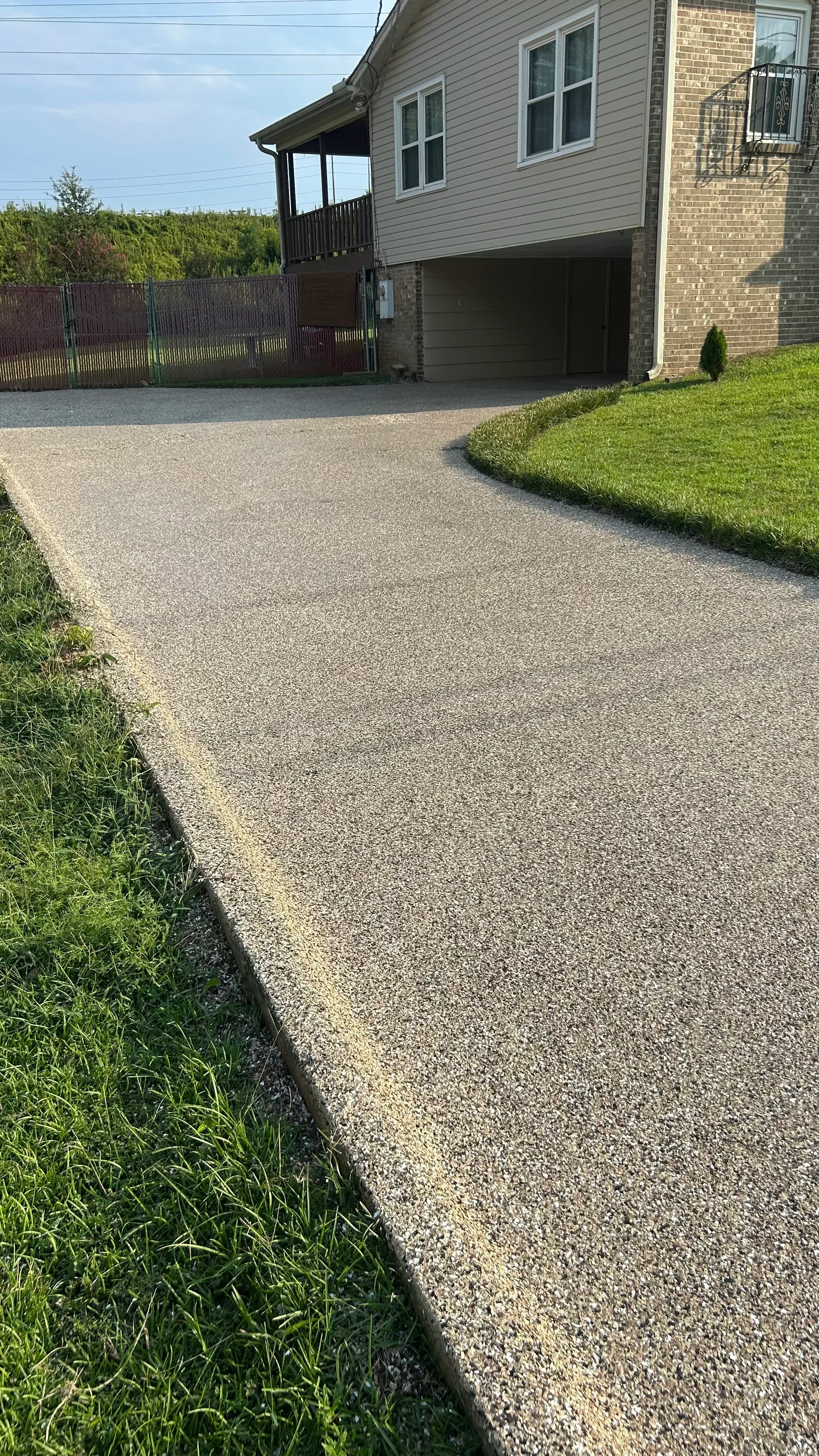 Newly resurfaced concrete driveway with aggregate finish and clean edges