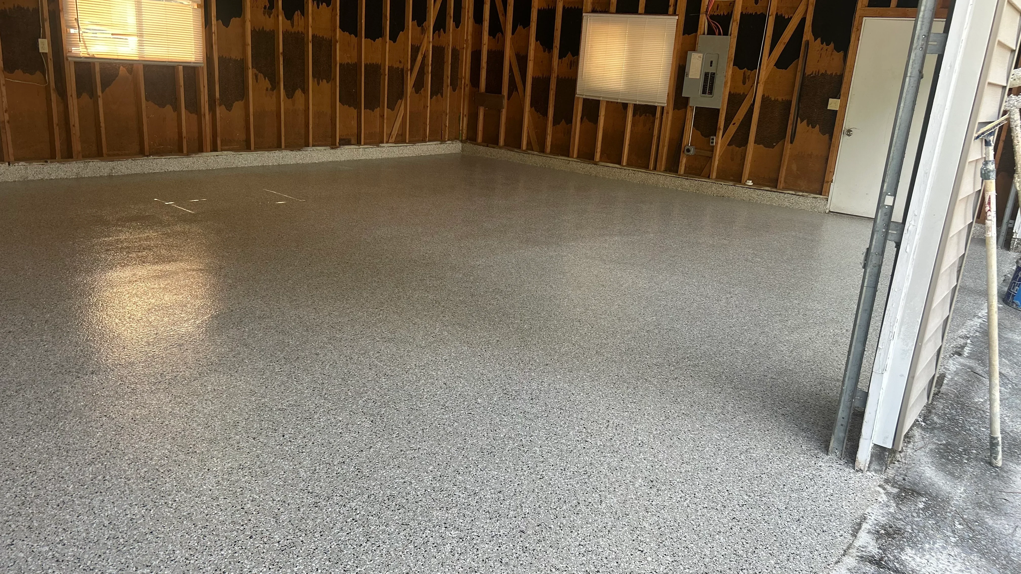 Gray speckled epoxy-coated garage floor with uniform finish and protective sealant