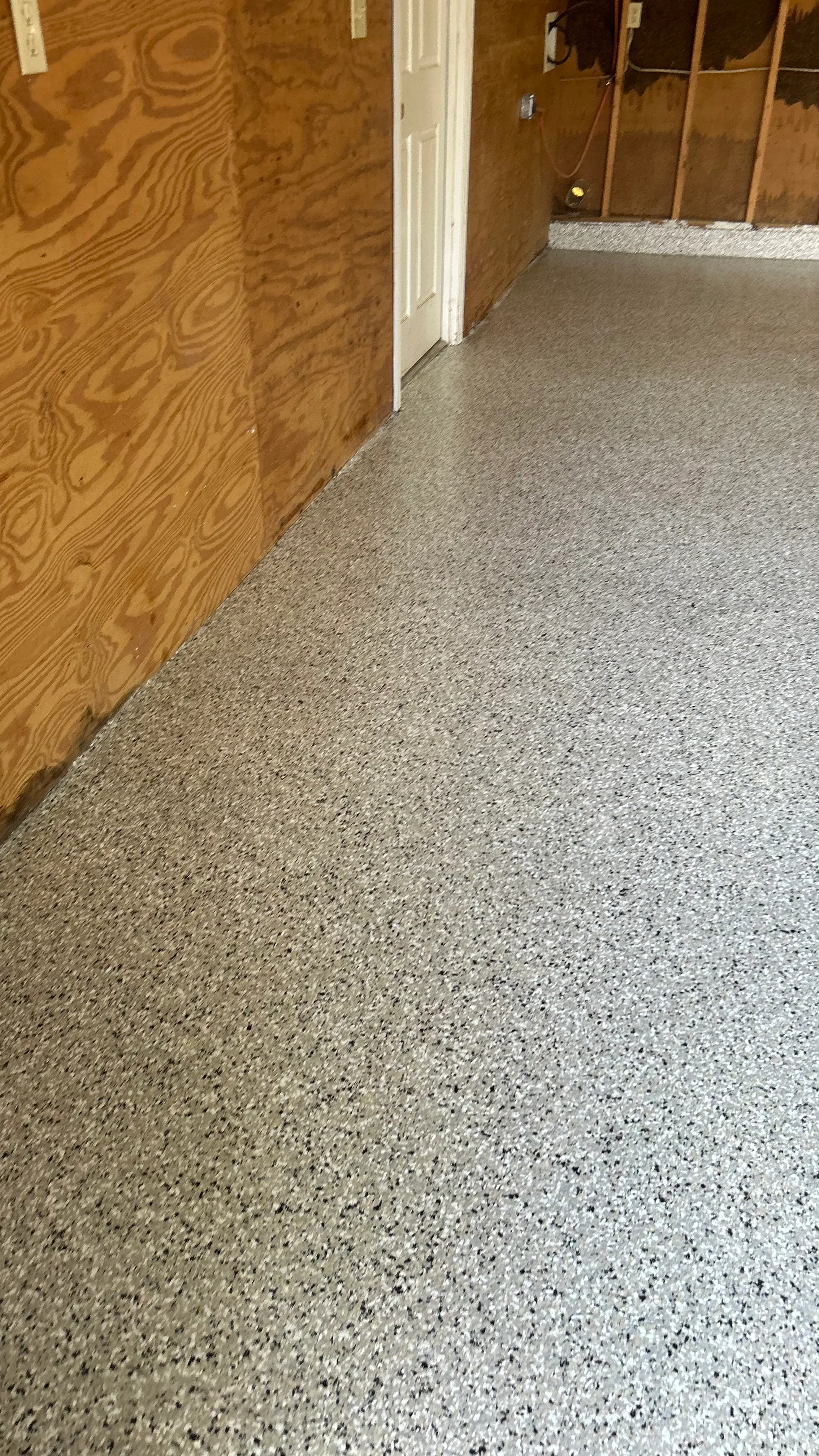 Polished concrete floor with light gray aggregate finish in interior room with framed walls