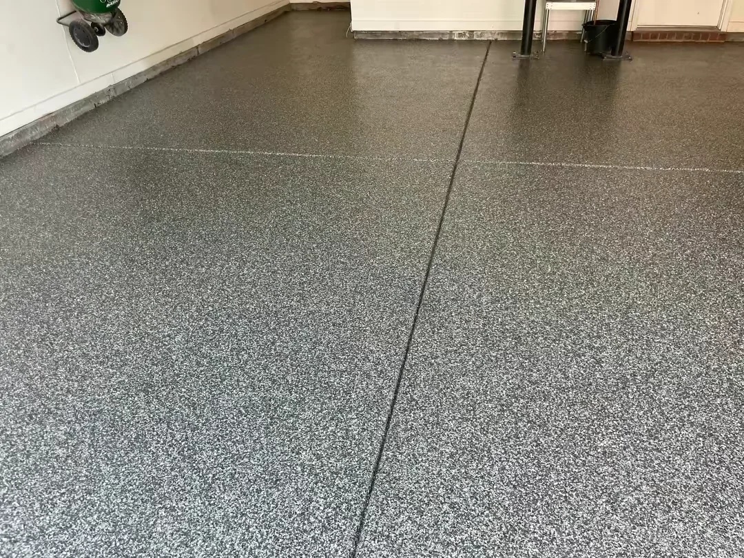 Finished epoxy garage floor with gray speckled coating and control joints