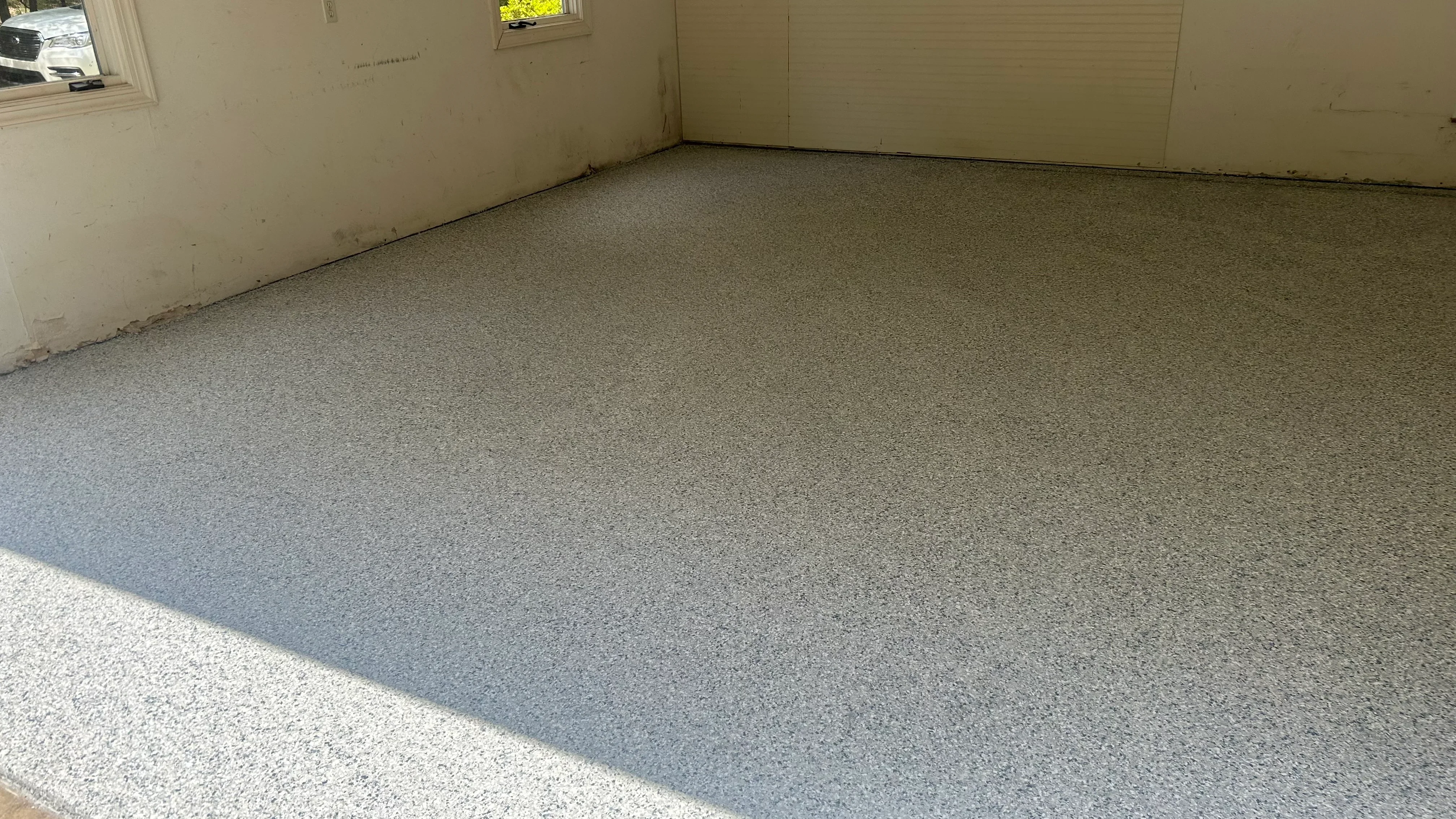 Finished epoxy garage floor with gray speckled coating and clean edges
