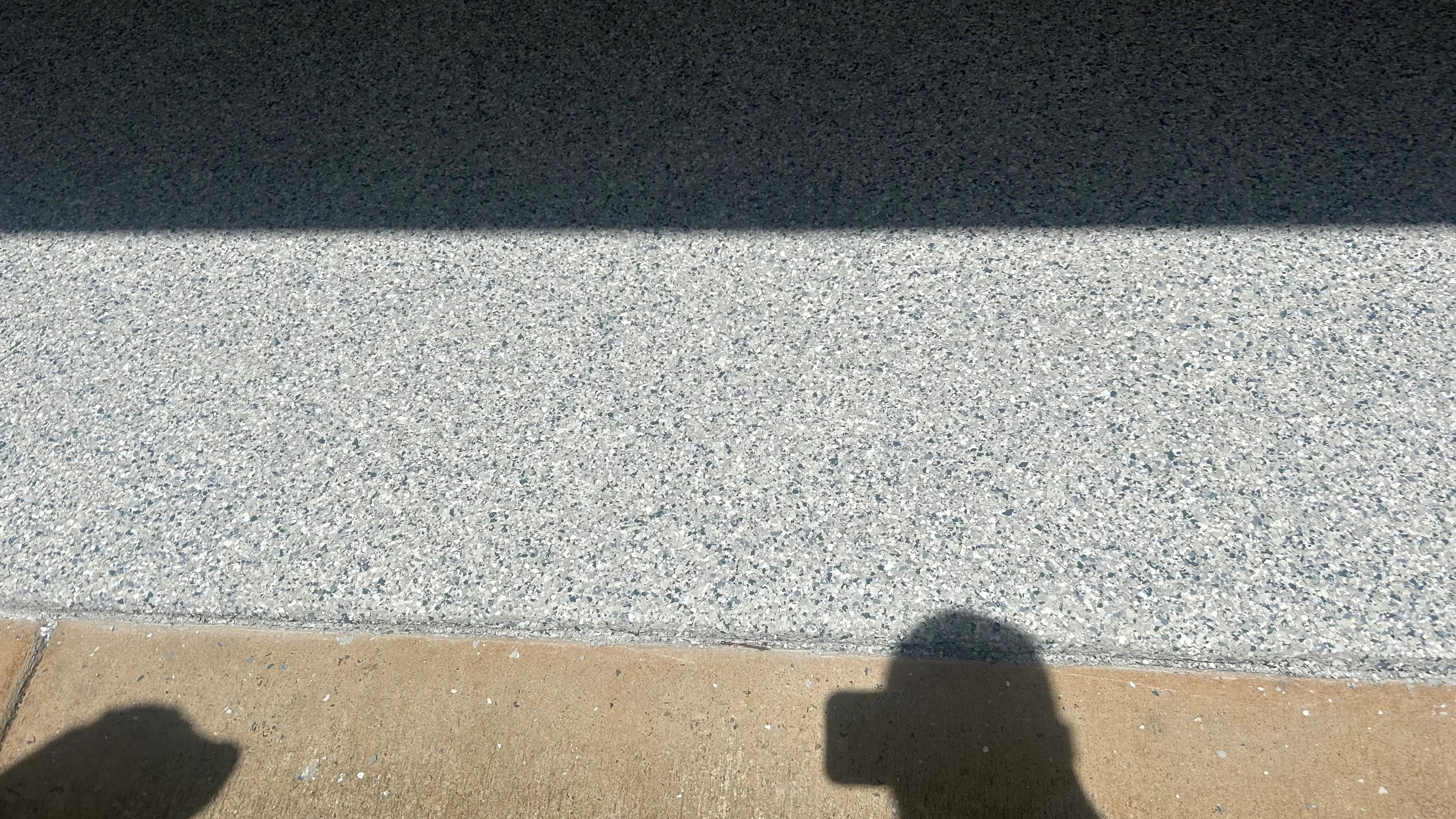 Decorative concrete overlay with light gray and charcoal aggregate finish showing clean edge lines