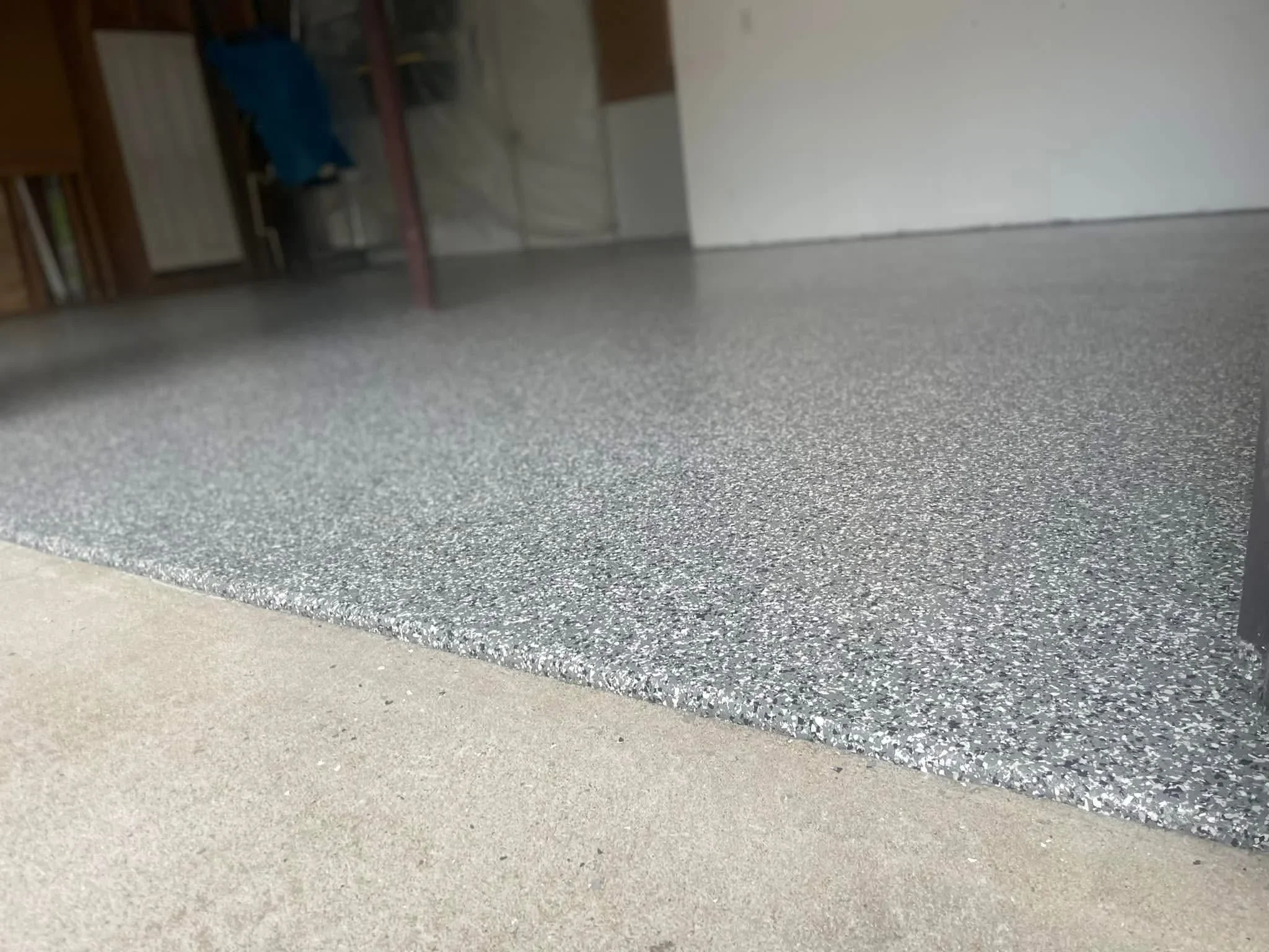 Gray epoxy-coated concrete garage floor with speckled aggregate finish and clean edge detail